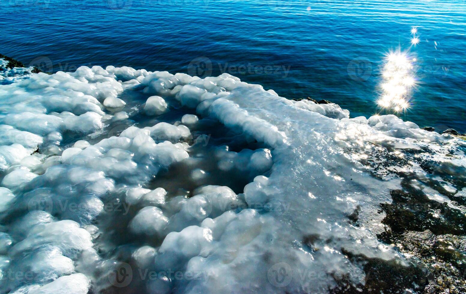 Icing of a concrete pier in the Black Sea, blocks of melted ice glisten in the sun, ice by the sea, Odessa photo