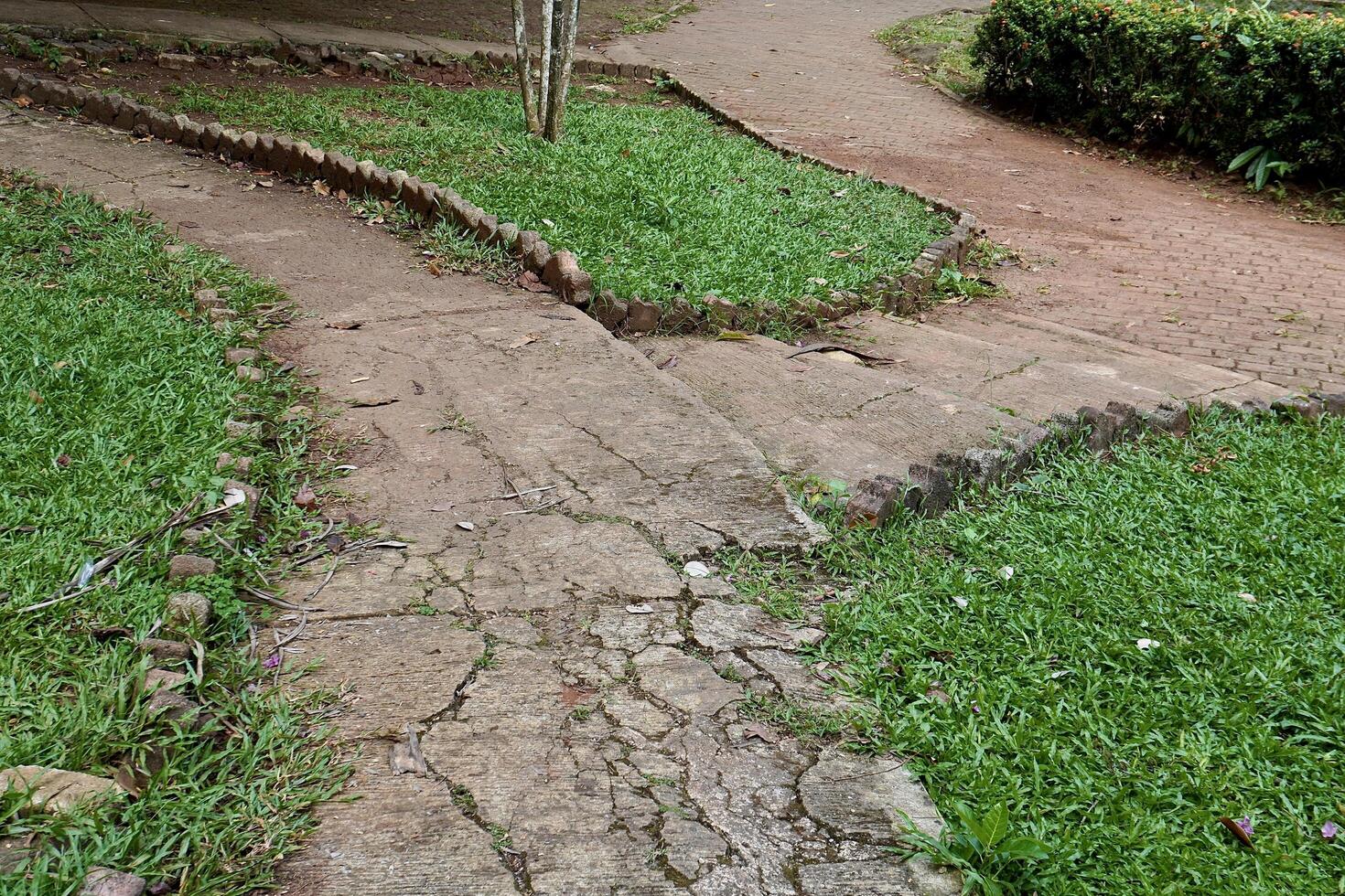 T junction or pertigaan damaged stone concrete country side road walk way isolated on horizontal green grass background. photo