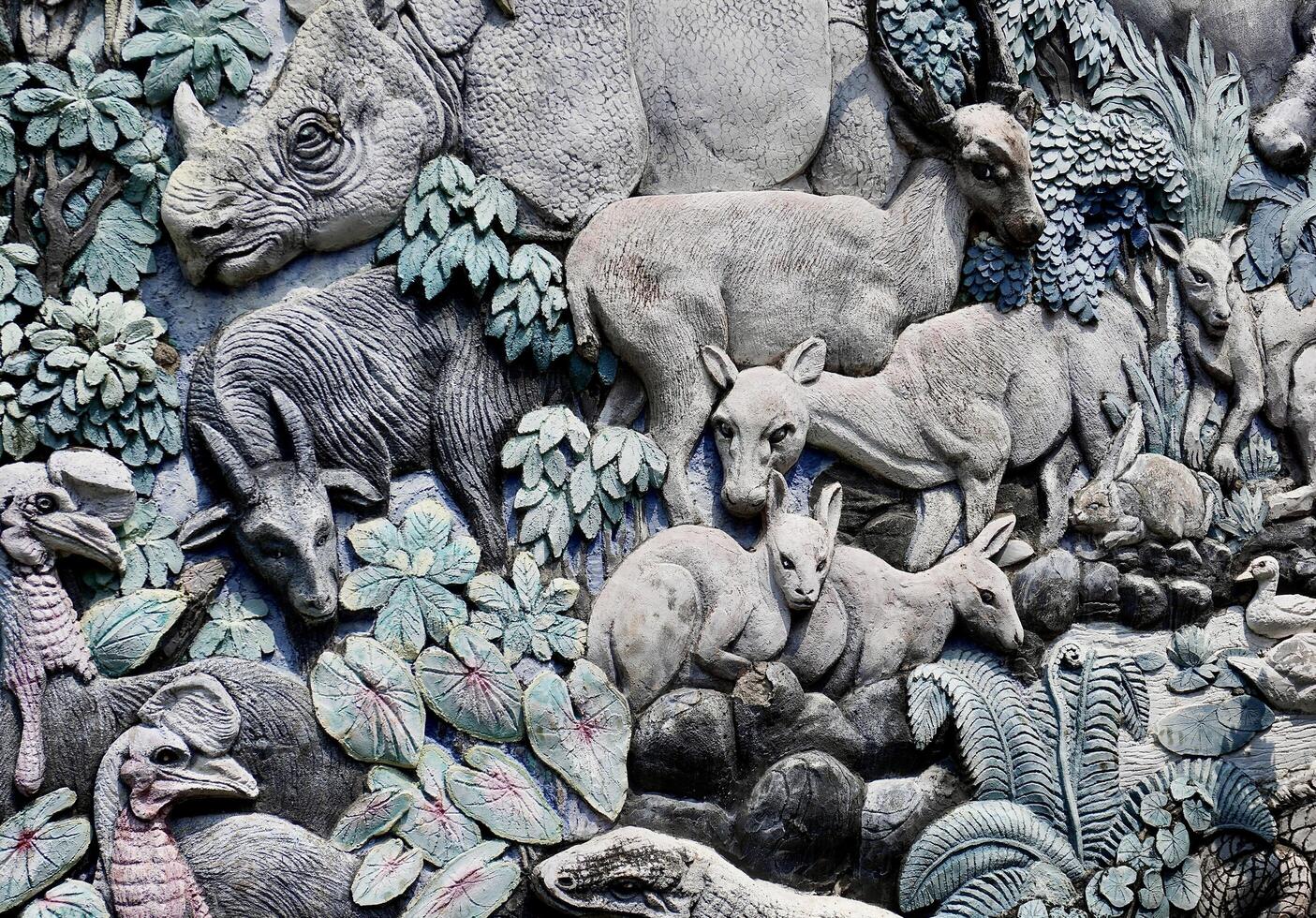 Jakarta, Indonesia - July 24th, 2024 - Rhino, komodo, and mousedeer wild animal pattern carving design isolated on horizontal stone wall background. photo