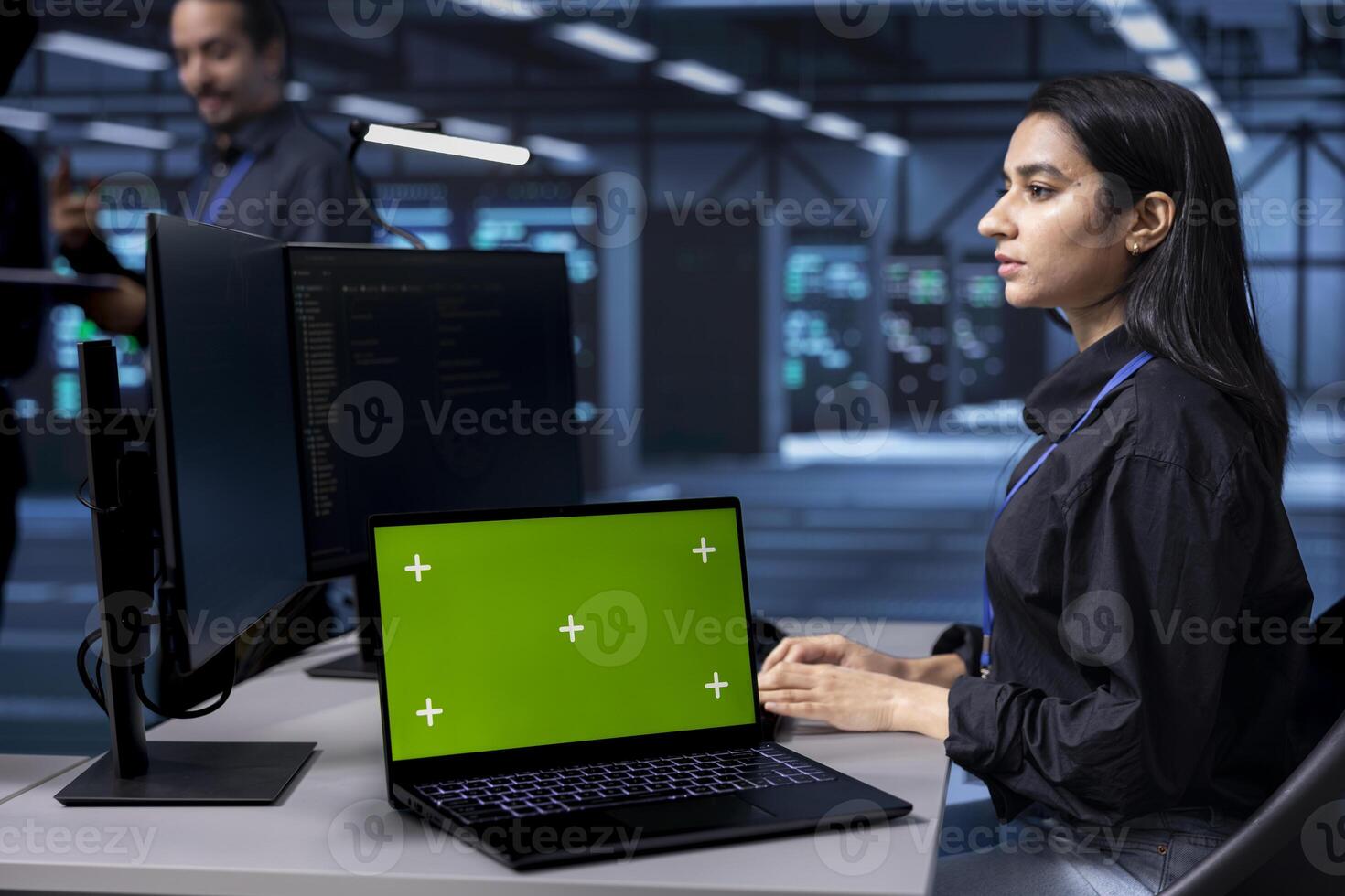 Admin working on green screen laptop in data center housing storage devices. Woman using chroma key notebook in facility with networking components providing vast amounts of computing resources photo