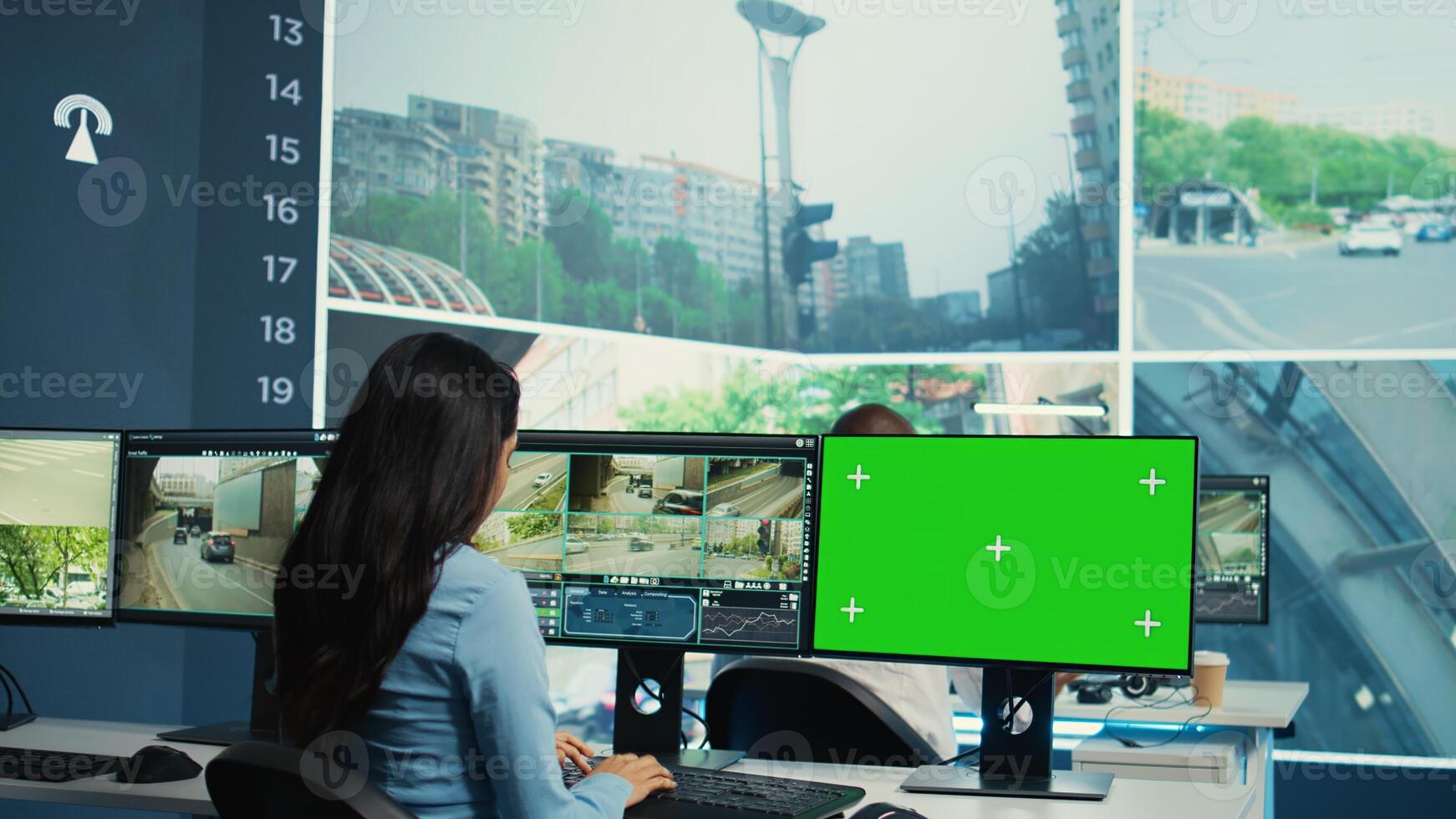 Indian woman working with surveillance footage and greenscreen on computers, tracking cars in traffic and at red lights. Government agency employee studies drivers behaviors. Camera B. photo