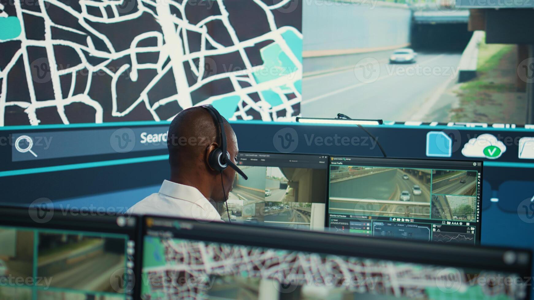 Operator uses satellite navigation map to guide delivery truck drivers, works in observation room to avoid traffic. African american employee tracing orders within the surveillance system. Camera B. photo