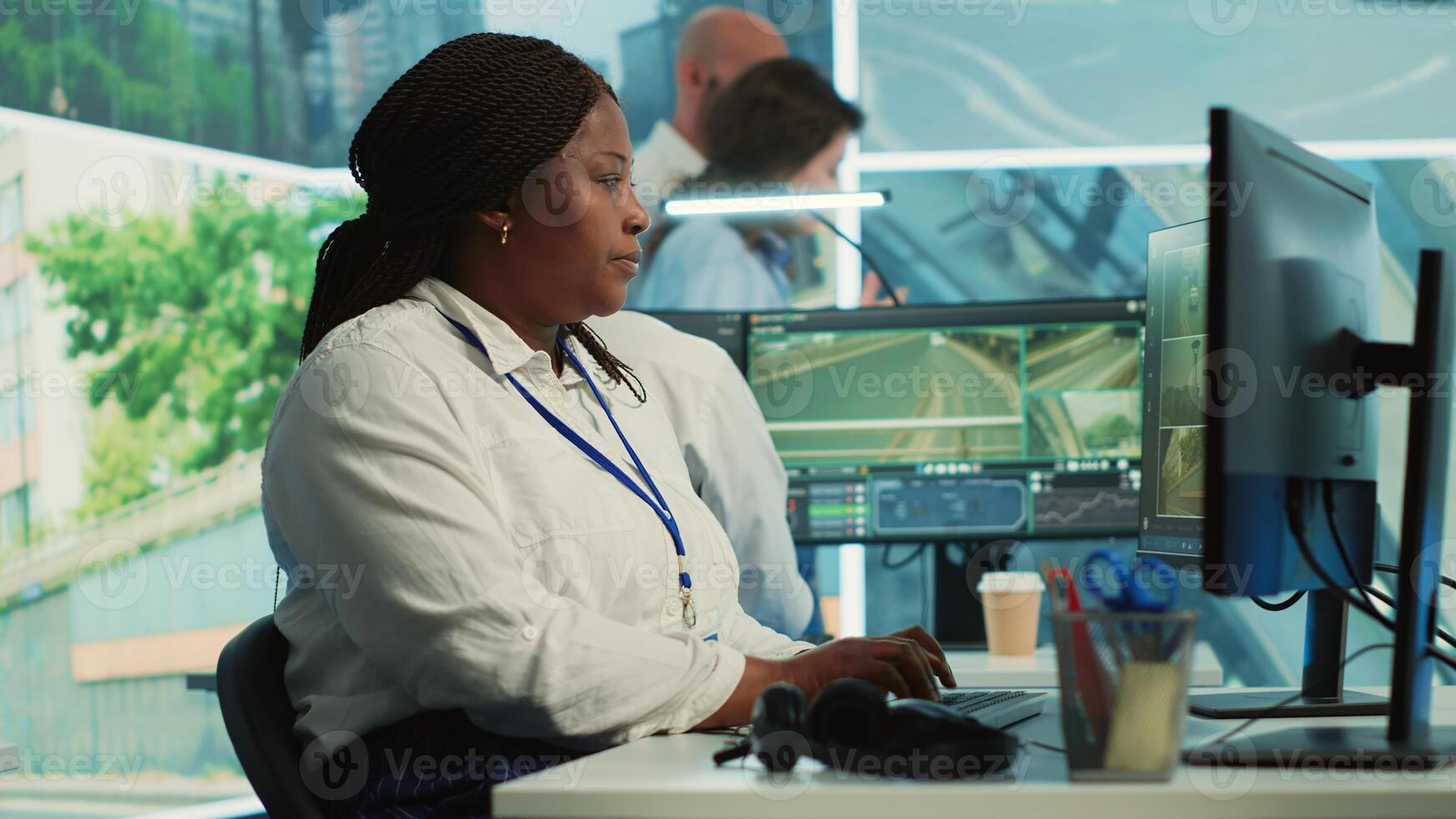 African american employee gathers data on cars in traffic through red light radar CCTV system, using real time surveillance footage for government safety activity. Camera A. photo