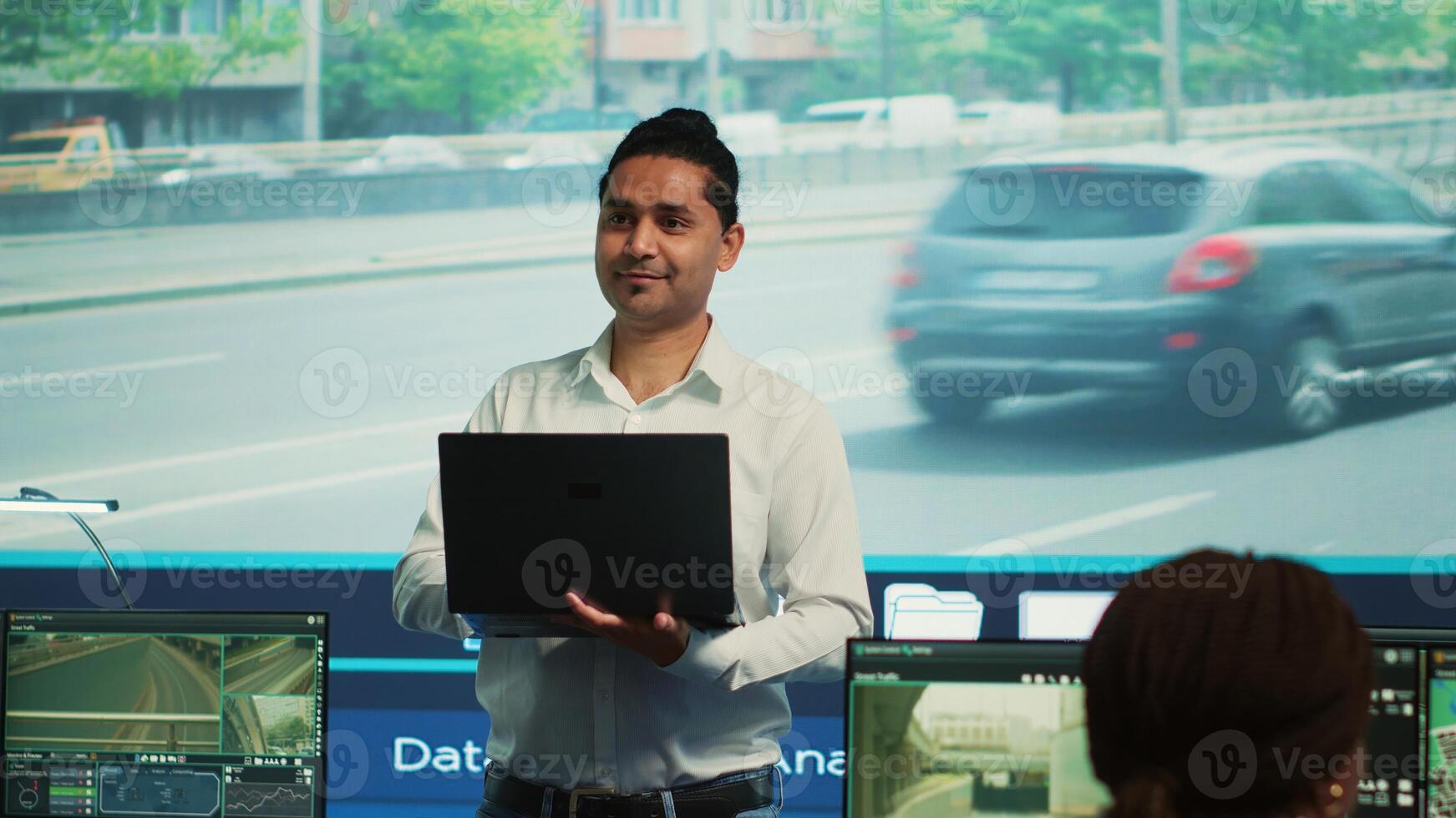 Indian man team leader coordinating his staff to observe urban surveillance footage through the CCTV security system. Government agency employees monitoring traffic via satellite cameras. Camera A. photo