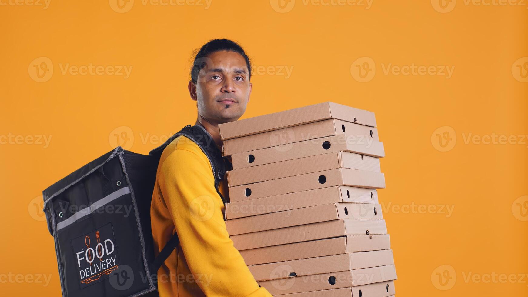 Indian delivery worker offering takeaway order to customer paying with debit card. Client buying meal from courier, swiping card on POS device, studio background, camera B photo