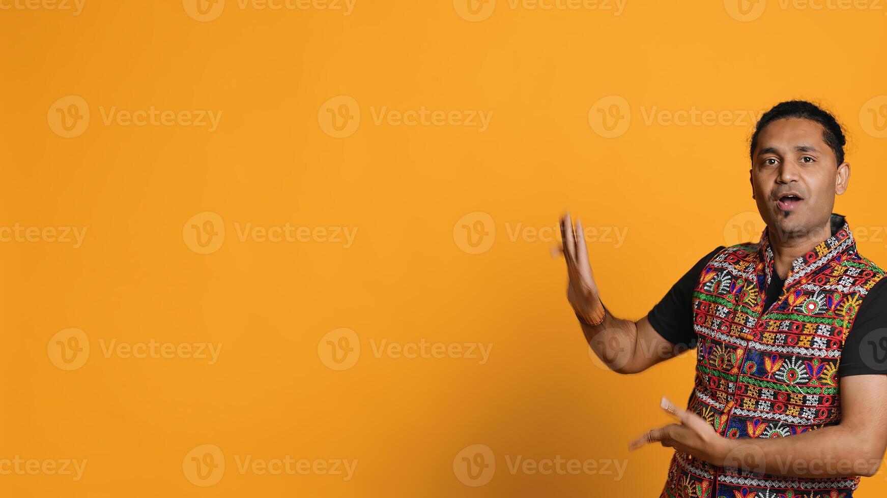 Radiant person having fun, dancing on oriental music, enjoying relaxation time. Joyous man doing entertaining bollywood dance moves, isolated over studio background, camera A photo