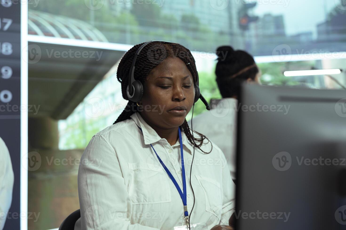 African american woman looks at real time surveillance footage and reporting illegal driving activity based on plate recognition radar system. Employee operating on CCTV security cameras. photo