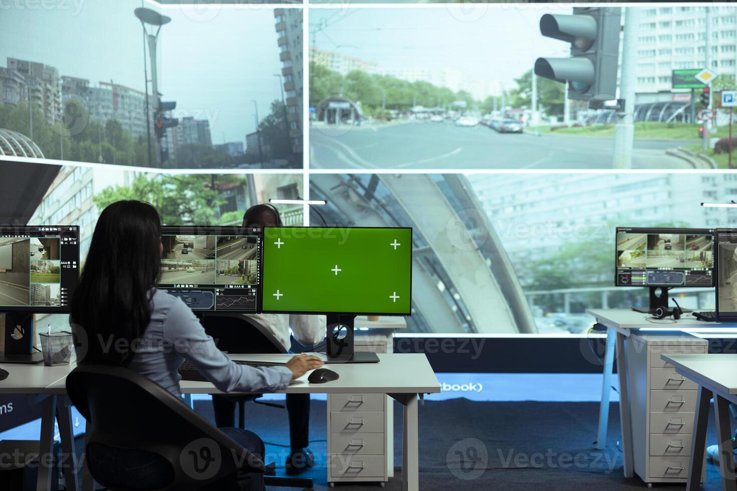 Indian woman working with CCTV footage and greenscreen on computers, collecting license plate data on cars. Government employee studies drivers behaviors in traffic, surveillance. photo