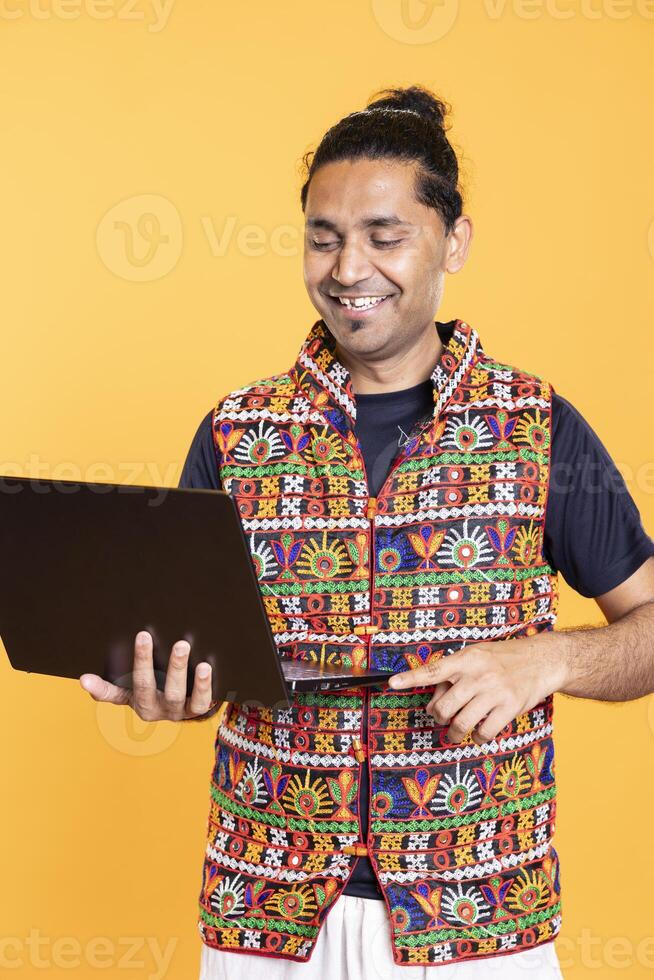 Portrait of jolly man grinning, happy after solving business tasks using laptop, isolated over studio background. Joyous employee celebrating finishing company budgeting using on notebook photo