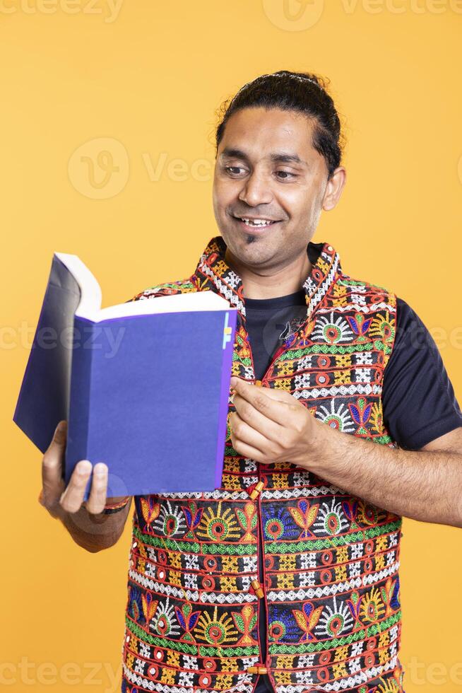 Joyous man delighted to read book, having fun and enjoying plot, isolated over studio background. Happy person excited about novel, enjoying leisure time, appreciating literature photo