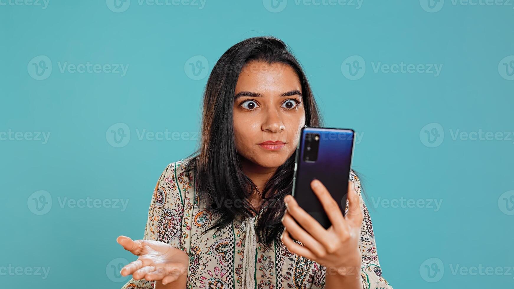 Irked woman fighting with friends during smartphone videocall, isolated over studio background. Outraged person arguing with mates during conversation on mobile phone, camera B photo