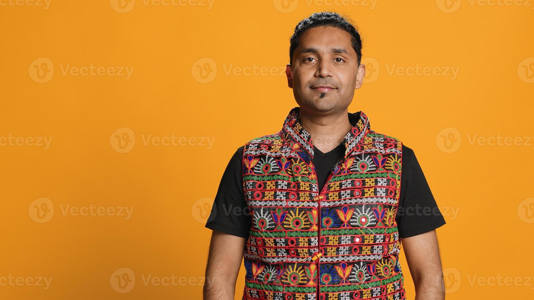 Portrait of jolly indian man with colorful garment smiling, looking pleased, isolated over studio background. Joyous person in traditional attire feeling carefree, camera A photo