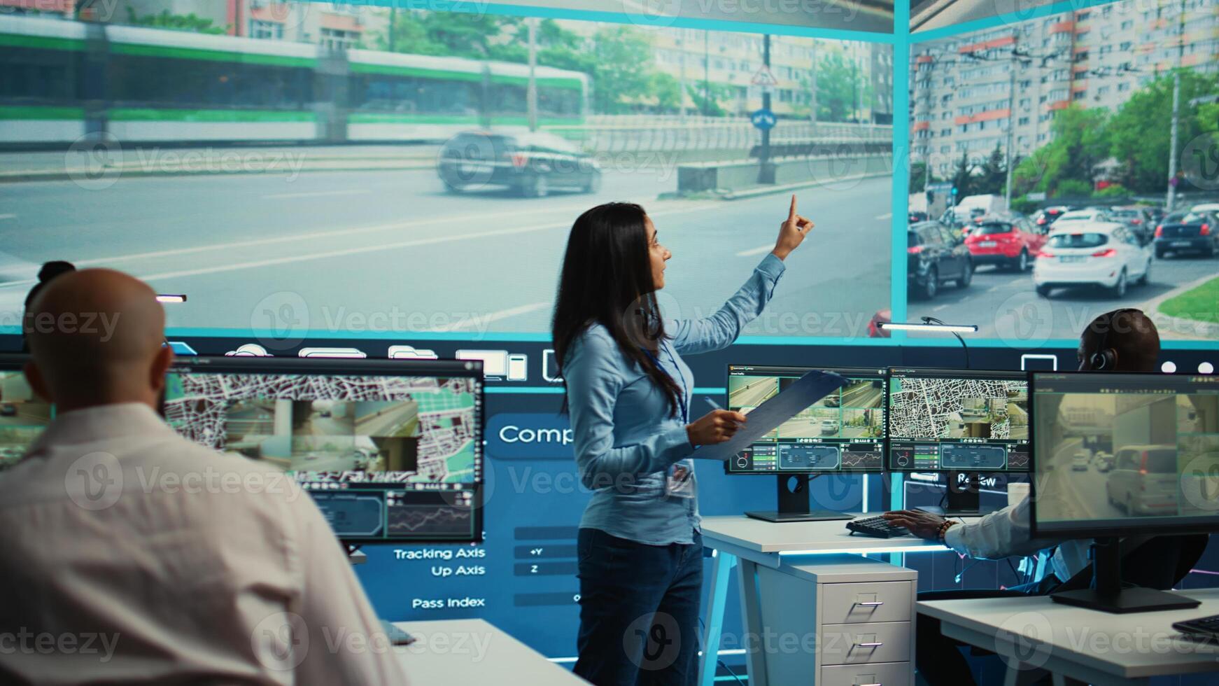 Indian supervisor assigning tasks for her operators team in observation room, people monitoring traffic through surveillance CCTV footage. Agency using satellite radar for public safety. Camera B. photo