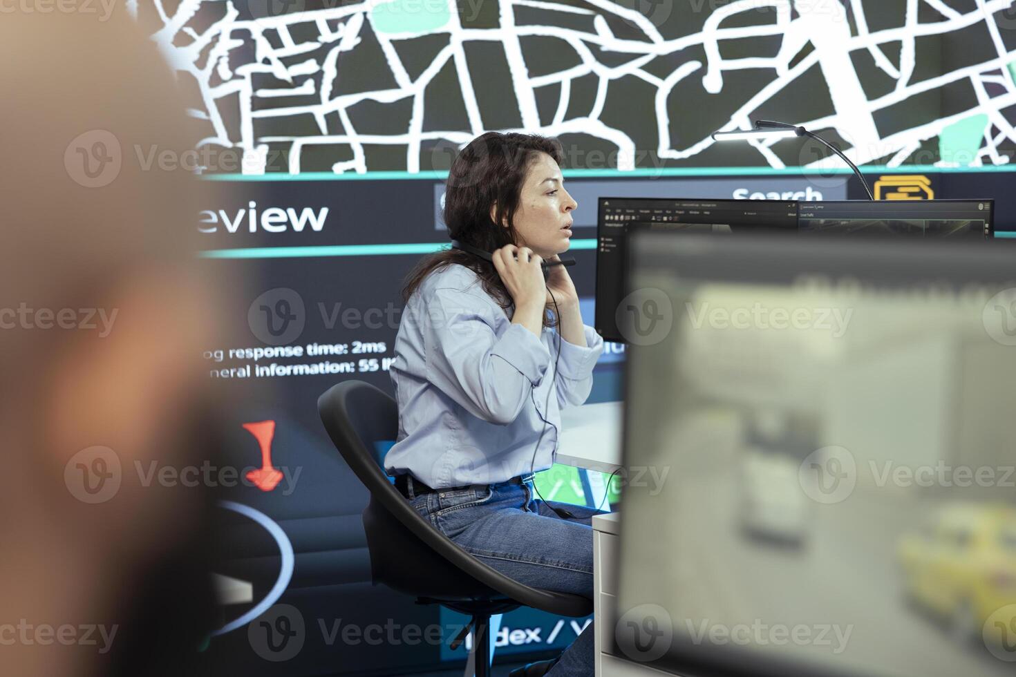 Call center operator puts headphones on to handle order delays complains from customers, working to ensure faster delivery time via satellite map and CCTV system. Cargo tracing. photo