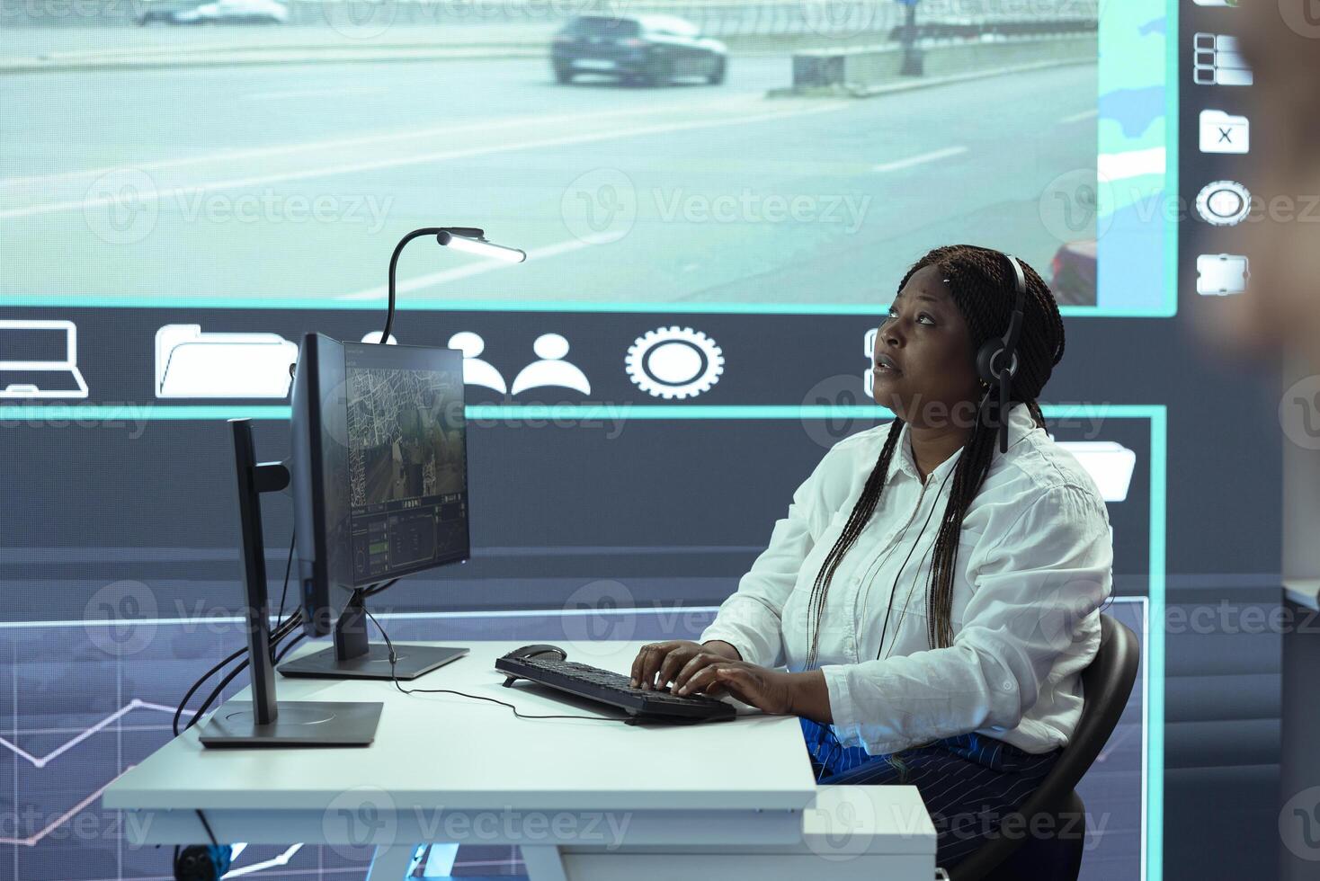 African american dispatch operator monitoring traffic activity on CCTV system surveillance footage, license plate reading and registering in the government database. High tech public security. photo