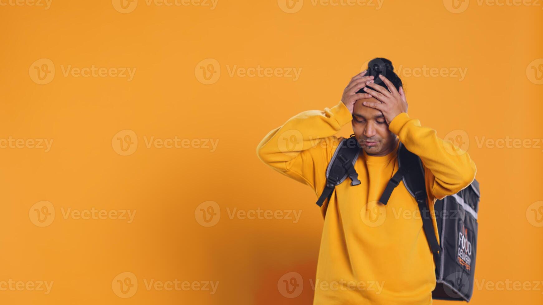 Overworked courier carrying huge stack of pizza boxes, rushing to serve clients, making mistake. Indian employee delivering too many food orders, falling on ground, studio background, camera B photo
