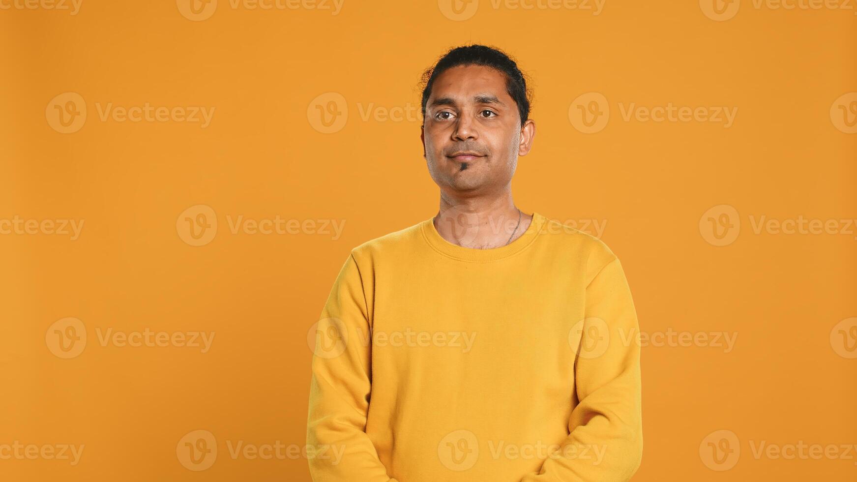 Portrait of radiant optimistic indian man with positive facial expression smiling, looking pleased. Calm merry person crossing arms, feeling satisfied, studio backdrop, camera A photo