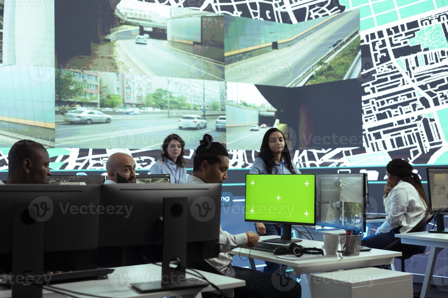 Indian dispatcher examines CCTV security footage and greenscreen, monitoring delivery truck drivers activity in traffic. Young call center operator follows couriers via surveillance system. photo