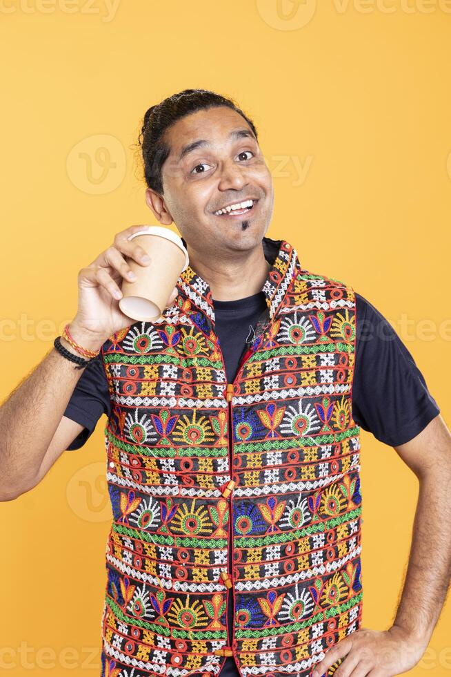 Portrait of radiant man sipping fresh coffee from cardboard cup early in the morning to wake up and be energized. Jolly person drinking hot beverage, having positive facial expression photo