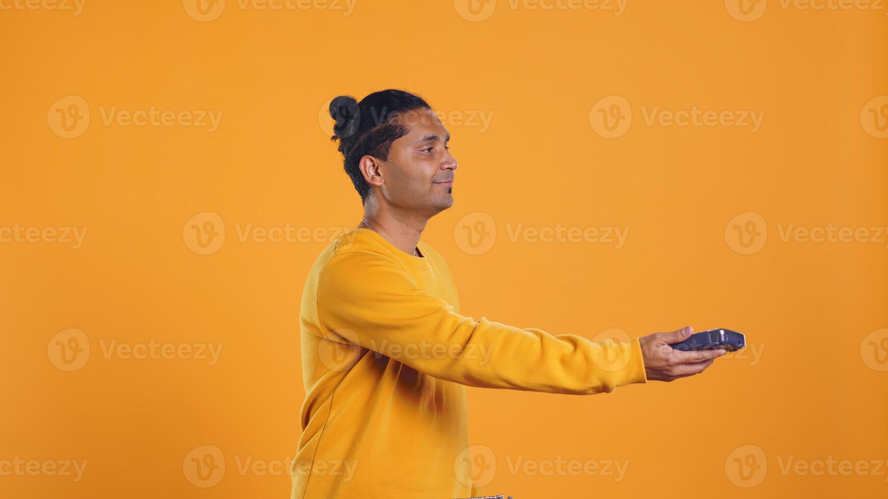 Indian pizza delivery worker getting takeaway order out of thermal backpack, giving it to client paying with card. Courier offering lunch paper bag and POS to customer, studio background, camera B photo