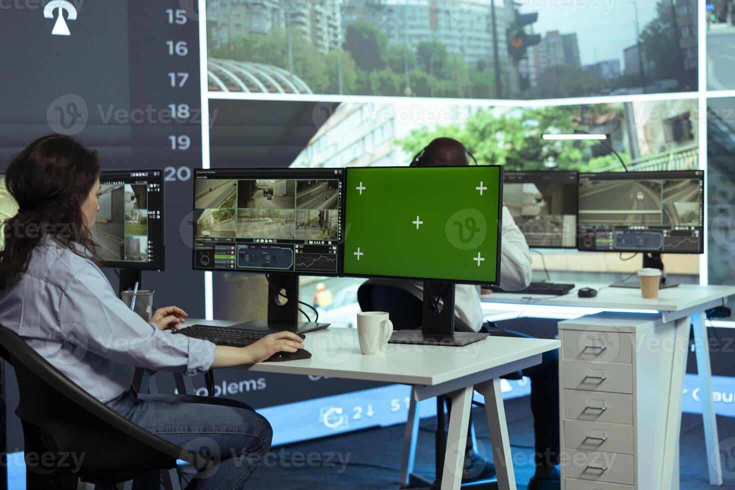 Operator monitors traffic next to an isolated mockup display, following real time surveillance footage from radar cameras system. Agency employee works with city CCTV intelligence. photo