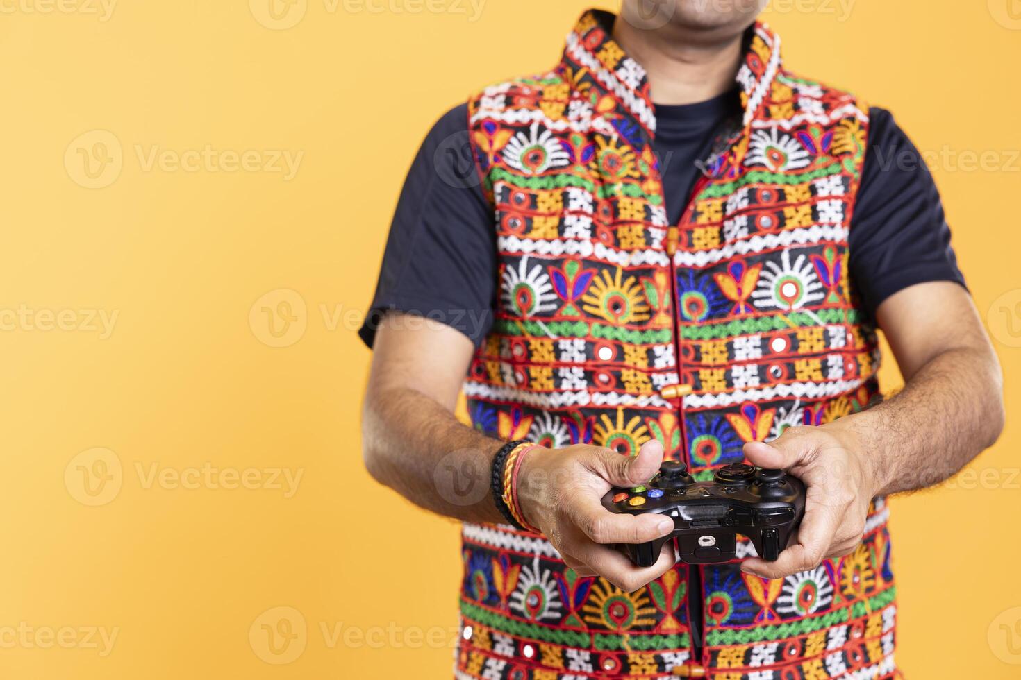 Close up shot of man wearing colorful vest playing videogames using controller, studio background. Gamer holding gamepad, participating in online multiplayer game using console system photo