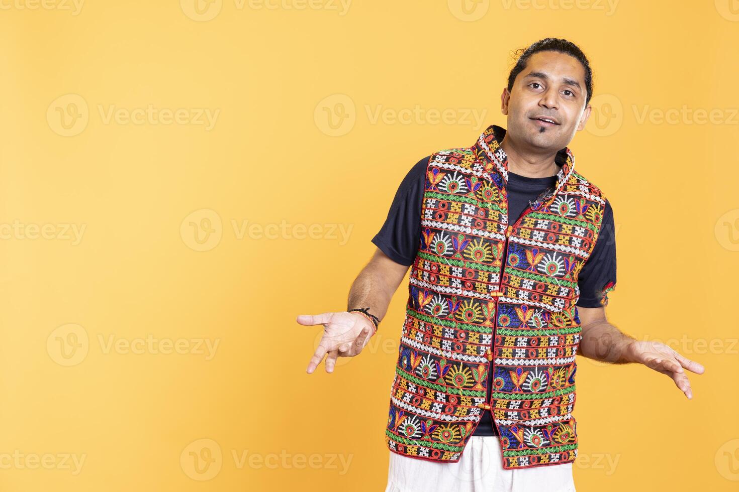 Portrait of upbeat man wavering, oscillating between answers, shrugging shoulders. Radiant person doing questioning hand gesturing, hesitating to provide response, isolated over studio background photo