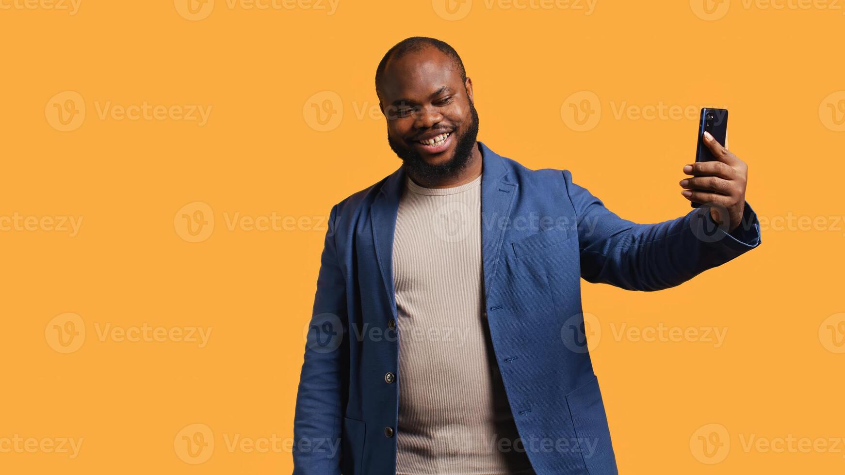 African american narcissistic man using cellphone to take selfies from all angles. Vain social media user taking photos using phone selfie camera, smiling happily, studio background, camera B