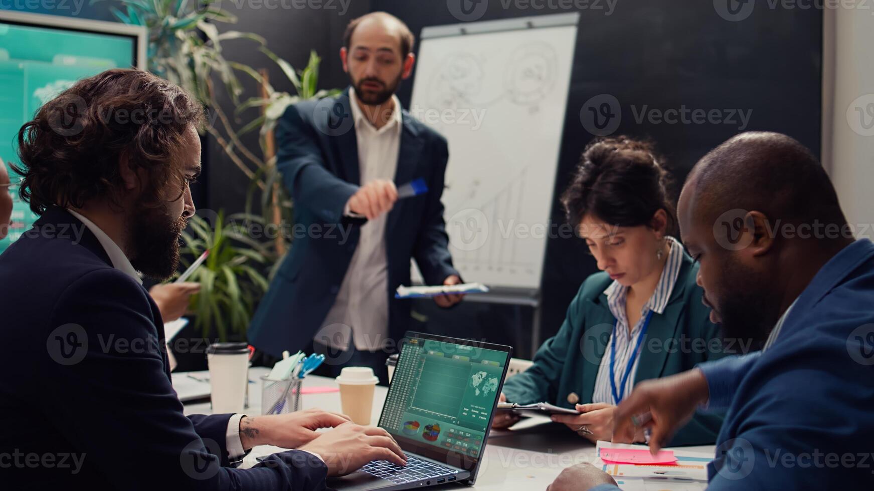 Team of associates working on resource allocation plans during a meeting, making important budgeting and staffing decisions to corelate with company objectives. Employees review strategies. Camera B. photo