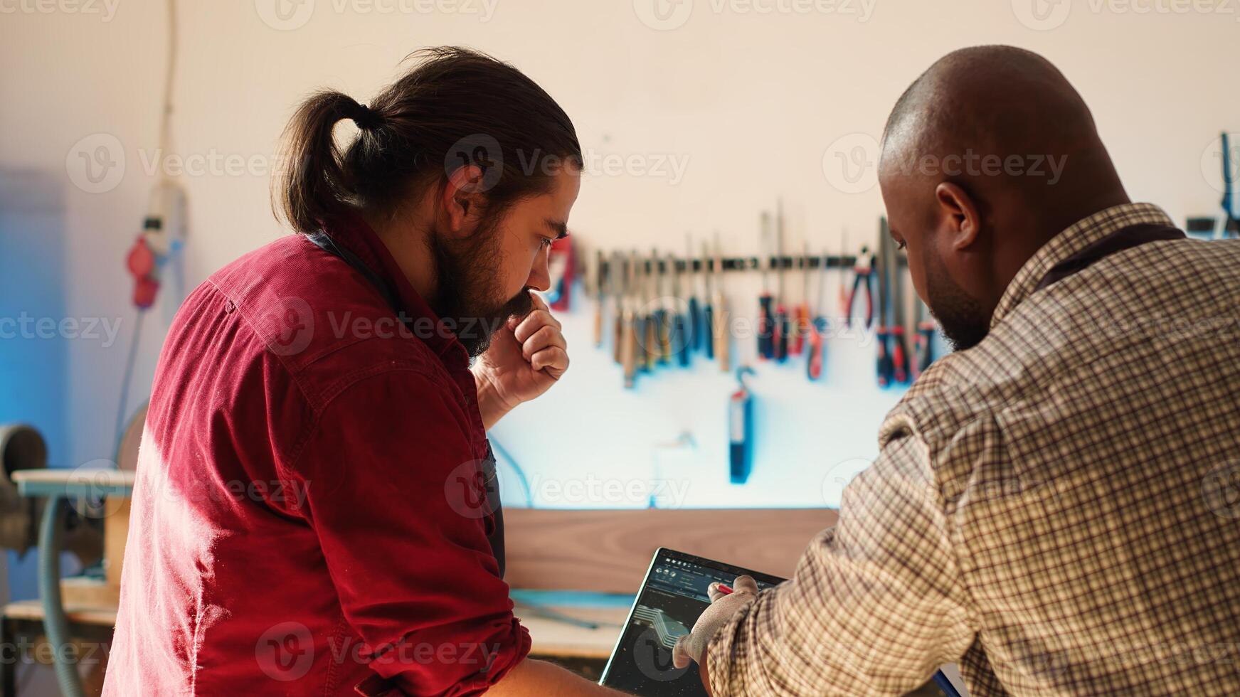 African american artist and colleague comparing wood art schematic with CAD software 3D render on laptop. Carpenters at work crosscheck drawing on clipboard with notebook blueprint, camera A photo