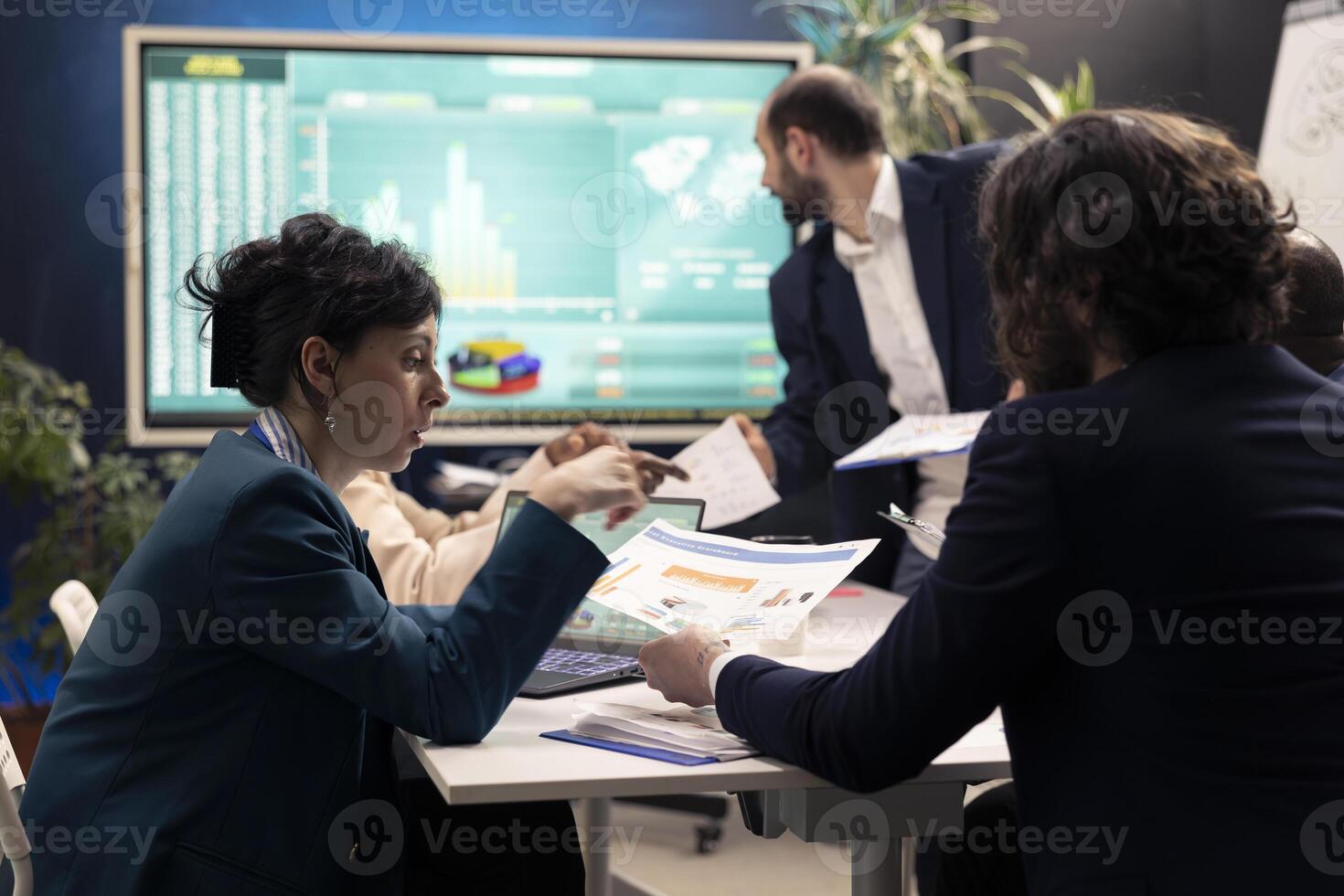Business team evaluate financial reports and success metrics on papers, using sales infographics for annual data reports. General director and staff members studying market demands and needs. photo