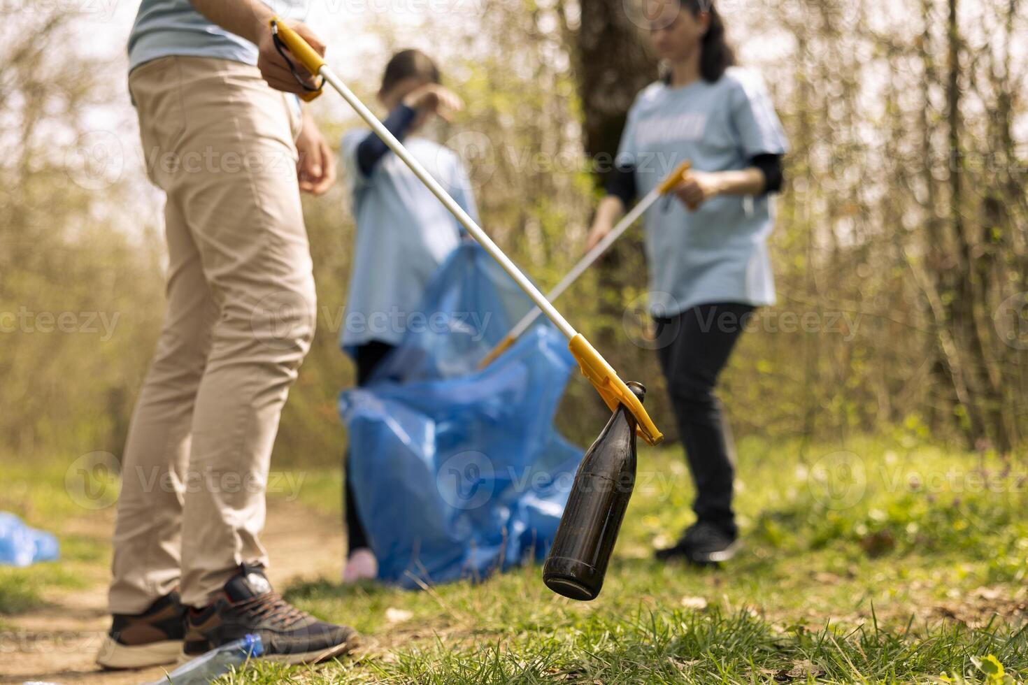 Team of volunteers collecting garbage and plastic waste to recycle, cleaning the natural habitat with litter cleanup equipment and bags. Activists grabbing rubbish from the forest, activism. photo
