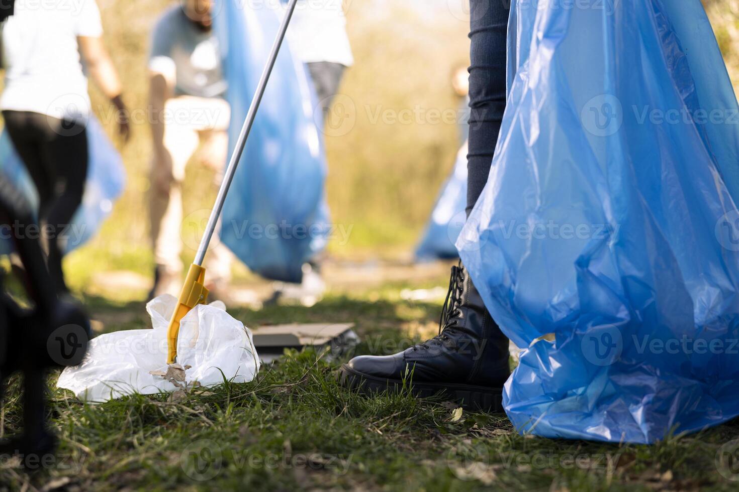 Activists collecting garbage to fix pollution issues within the natural ecosystem, protecting the environment. Volunteers group doing community service to clean the forest from junk. photo