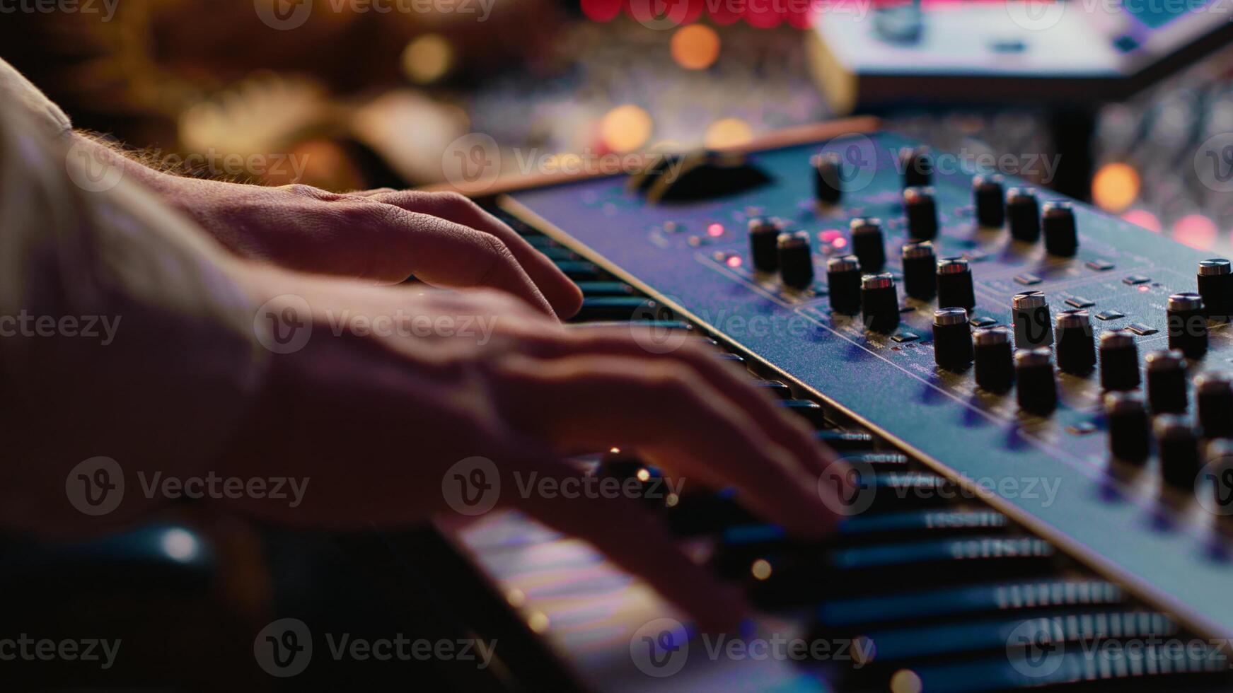 Young singer playing piano electronic keyboard in control room, recording new music with midi controller and mixing console. Talented composer practicing on synthesizer in studio. Camera A. photo