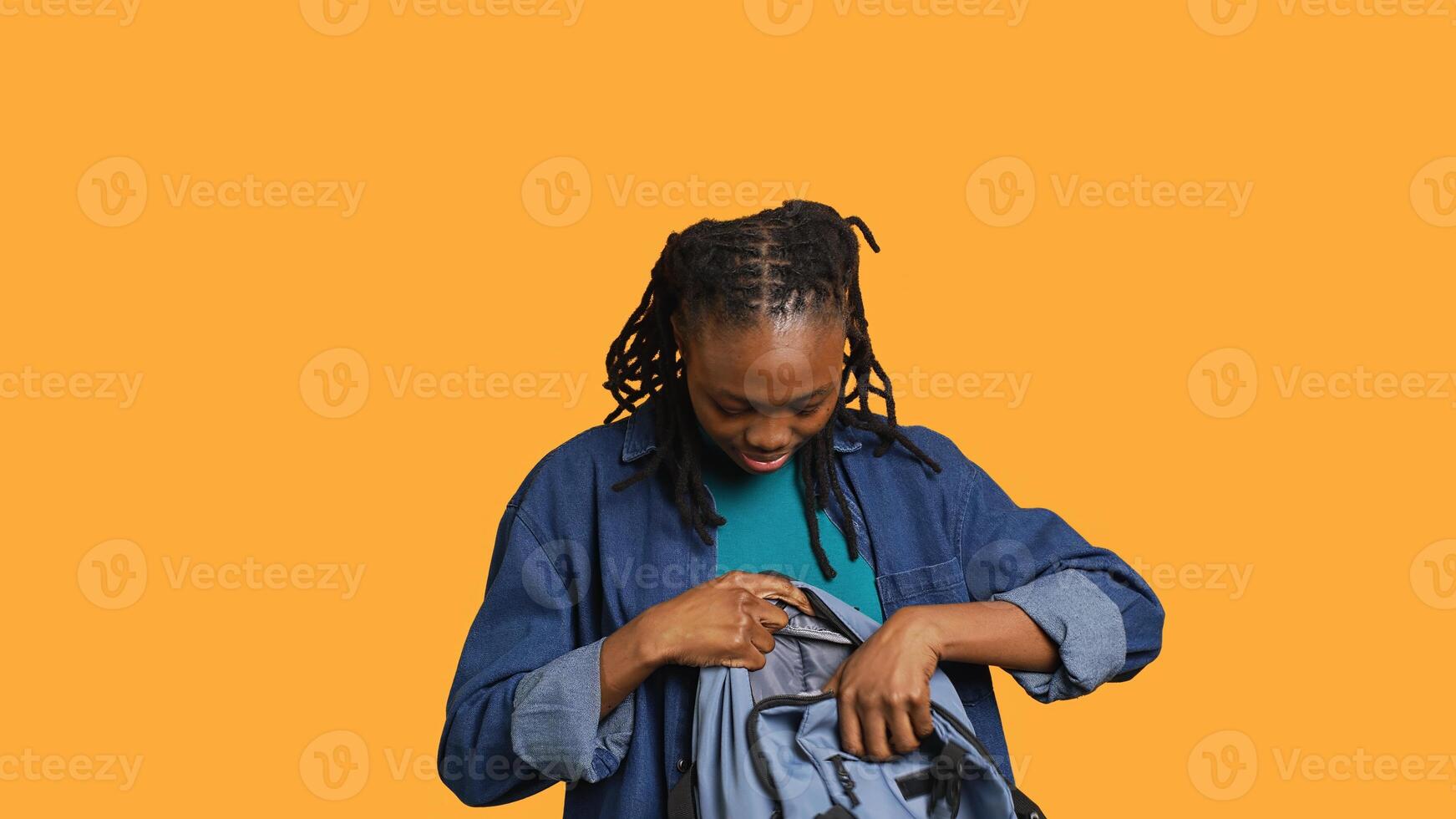 Happy BIPOC woman taking laptop out of backpack, preparing to start job shift, isolated over studio background. Smiling african american employee unpacking notebook, going to work, camera A photo