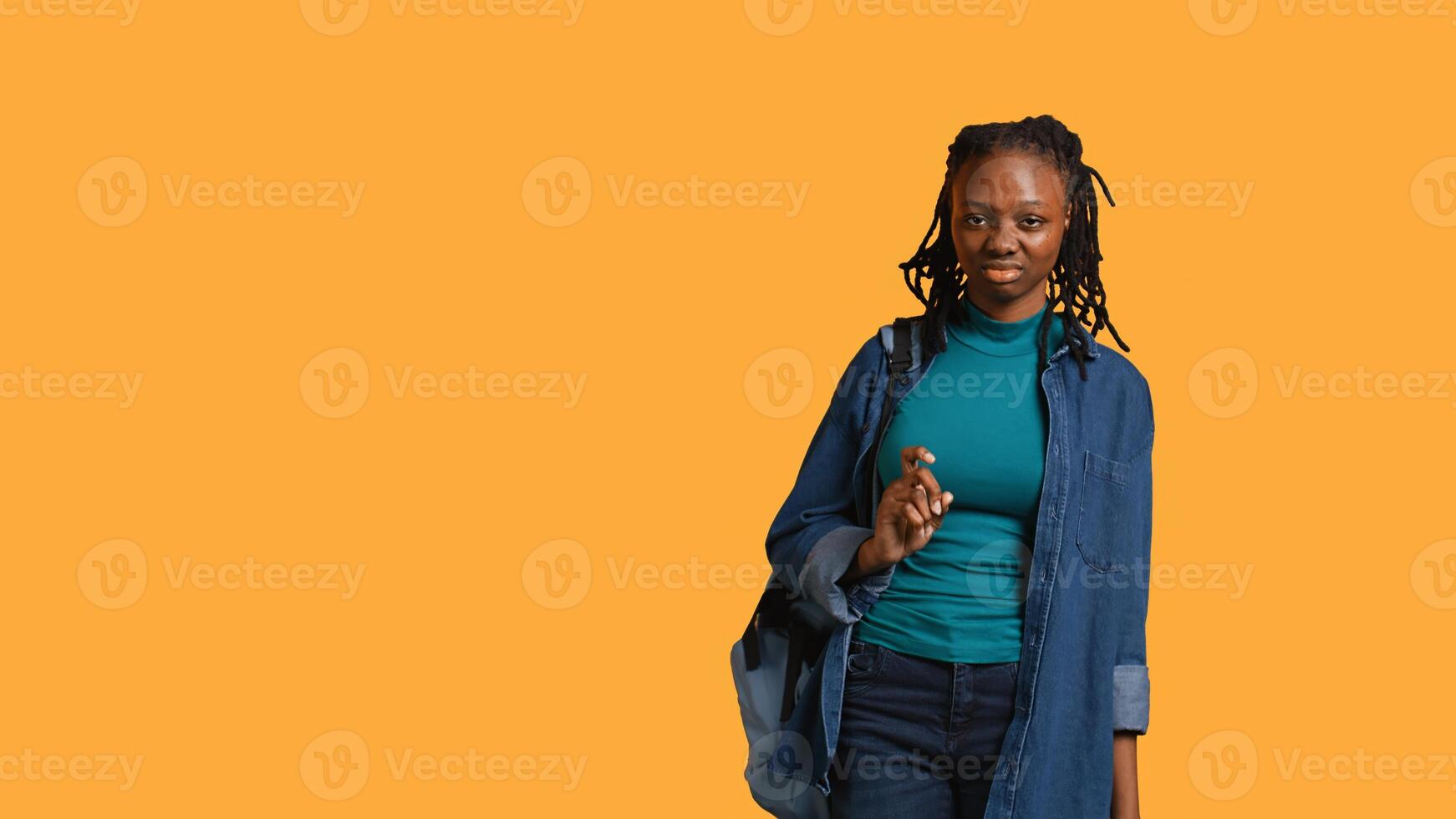 Anxious student at school thinking of raising arm to answer question but unsure of herself, studio background. Teenager lacking confidence needed to volunteer saying explanation to question, camera B photo