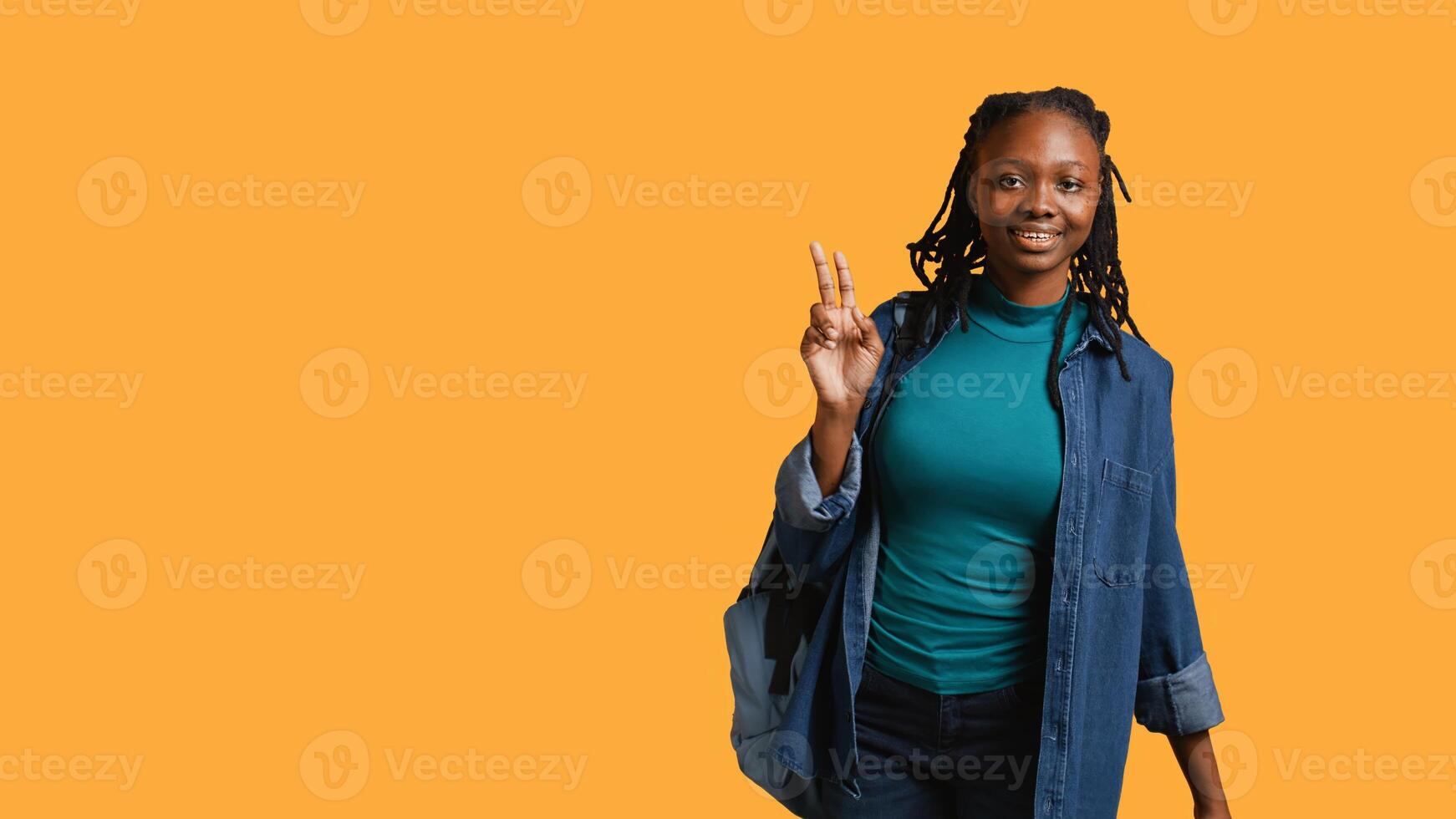 Smiling african american student at school raising arm to answer question, isolated over studio background. Cheerful girl with hand up volunteering to tell teacher explanation to question, camera B photo