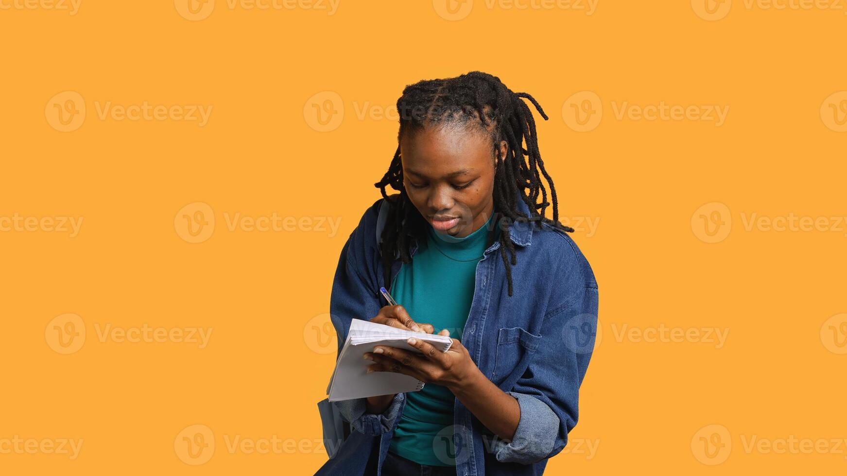 Girl with bad eyesight squinting eyes, trying to read lecture information and take notes at school on notepad, studio background. Student struggling to understand university class material, camera A photo