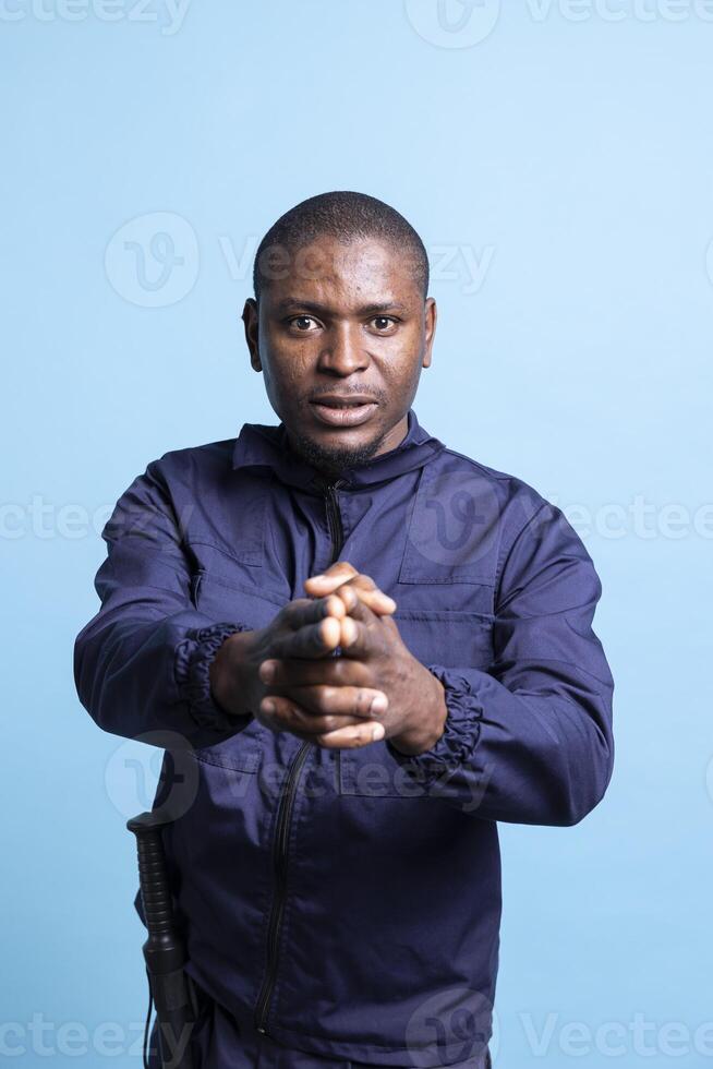 African american bodyguard pointing an imaginary gun at the camera, mimics target practice shooting. Portrait of confident security agent holds his hand in the shape of a weapon pistol. photo
