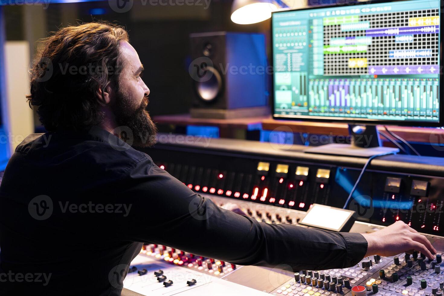 Audio technician operating daw software for mixing and mastering tunes in studio, editing music on control panel board. Skilled producer composing records with faders and switchers. photo