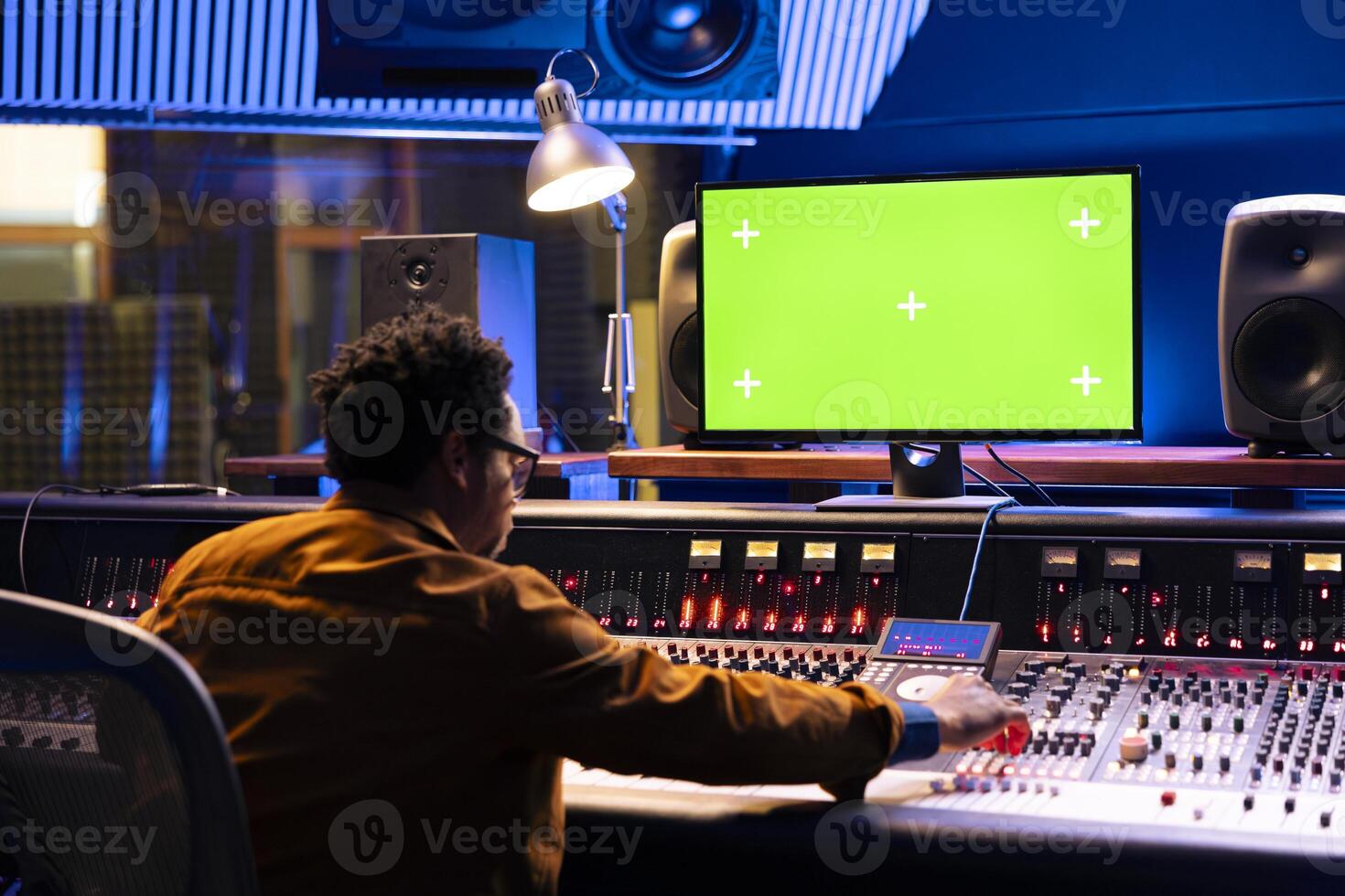 Music engineer working on mockup pc and mixing console with various knobs and faders in control room, editing tunes in post production. Young skilled producer creating sounds, technical equipment. photo