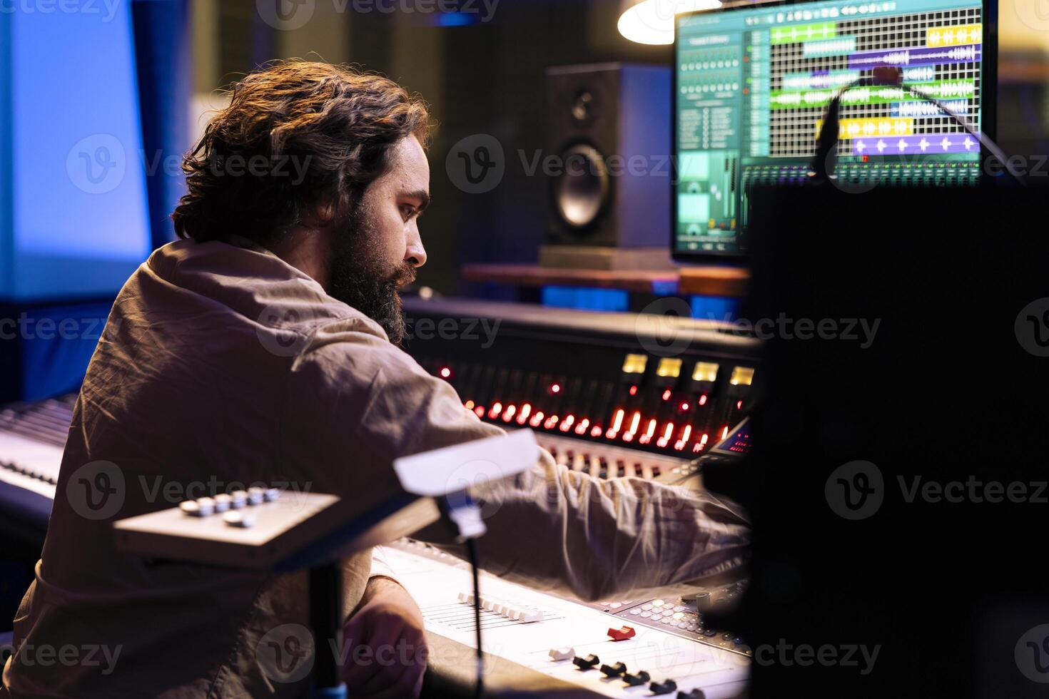 Audio technician working on recording and editing new music in studio, processing sounds by using mixing console and twisting knobs in control room. Sound producer pushing buttons and sliders. photo