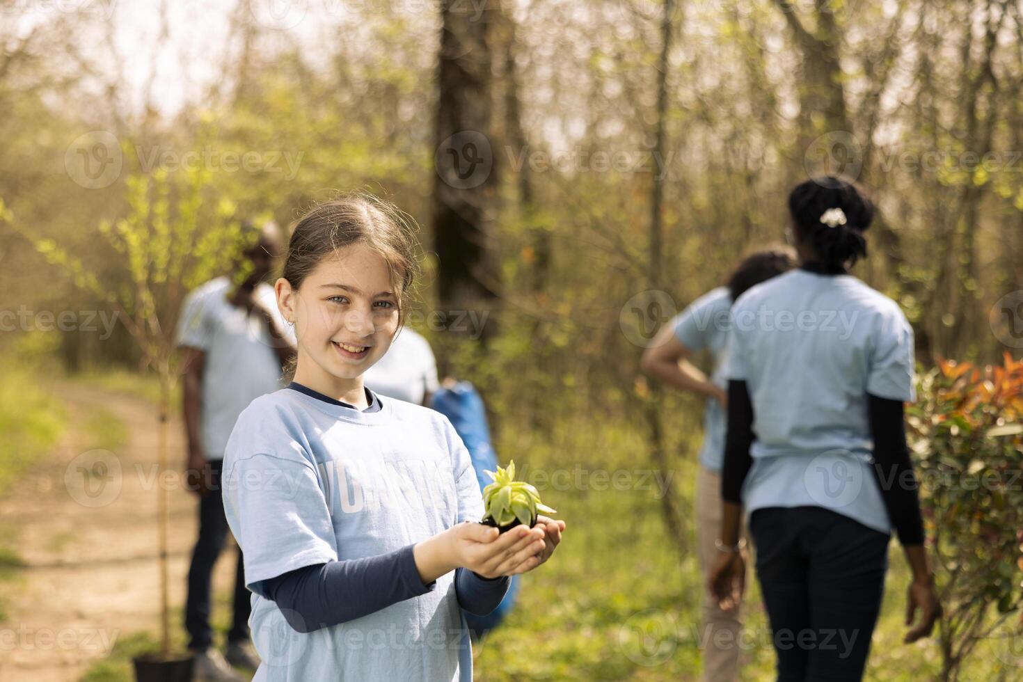 Cute little child getting ready to plant a small tree seedling in the forest, working to protect the natural environment and ecosystem. Young activist planting seeds to grow vegetation. photo