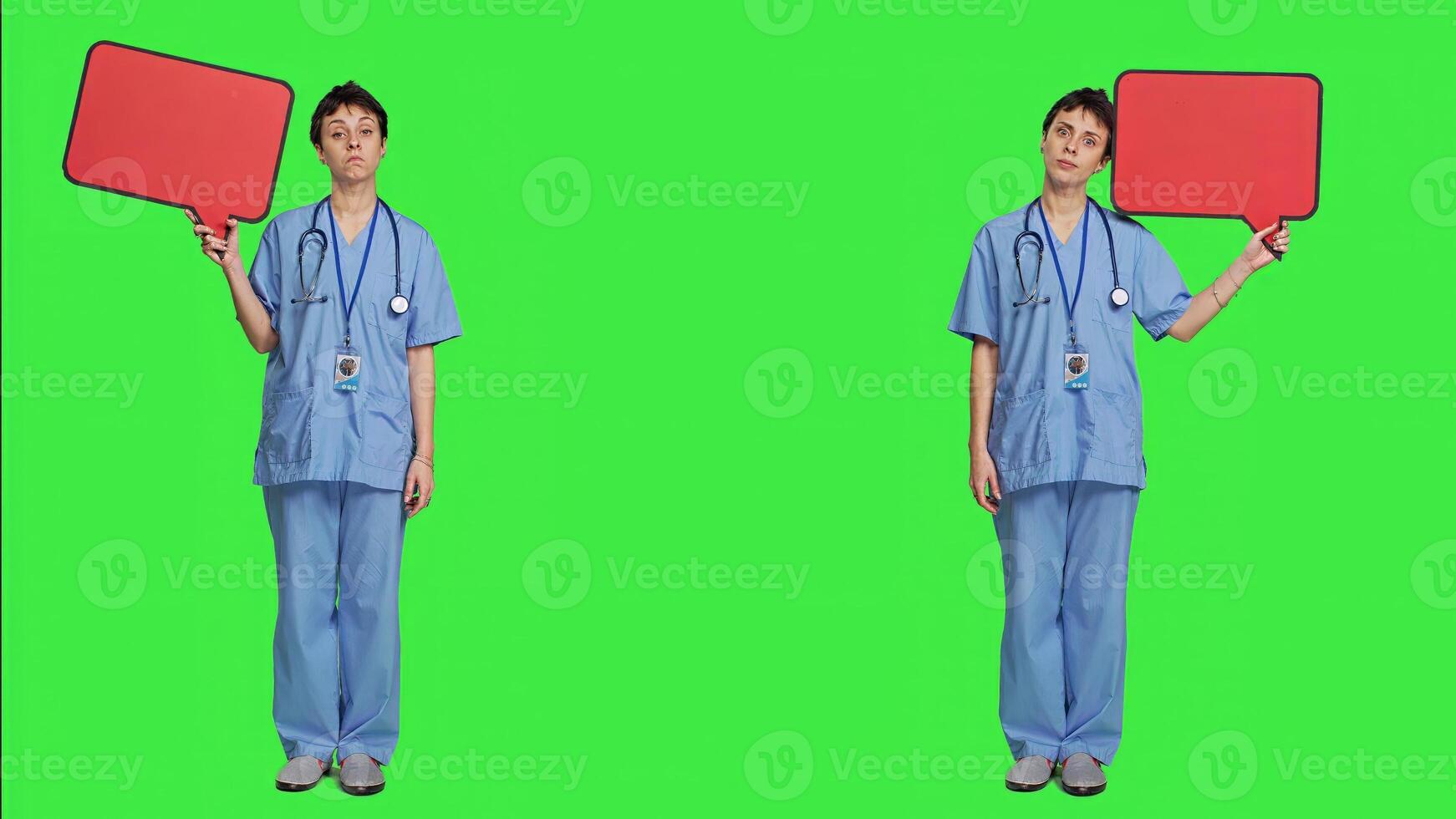 Medical assistant holding a red speech bubble icon against greenscreen, creating advertisement with empty copyspace billboard sign. Nurse shows cardboard poster, marketing announcement. Camera A. photo