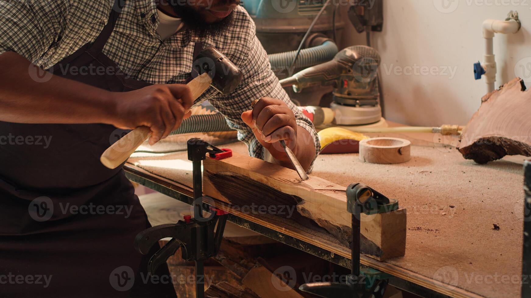 African american manufacturer shaping raw timber using chisel and hammer, creating wood art, making precise cuts. Artist making handmade wood sculptures, engraving lumber with tools, camera A close up photo