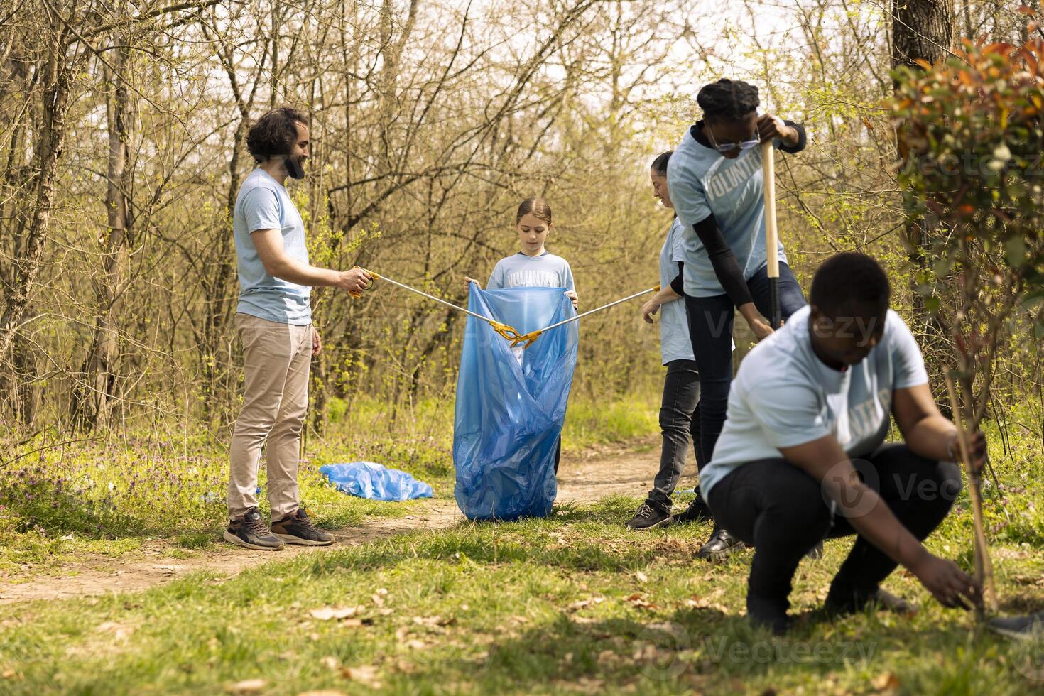 People collaborating to use proper tools and clean the forest, recycling plastic waste and fighting pollution. Activists team volunteering to collect rubbish from the woodland ecosystem. photo