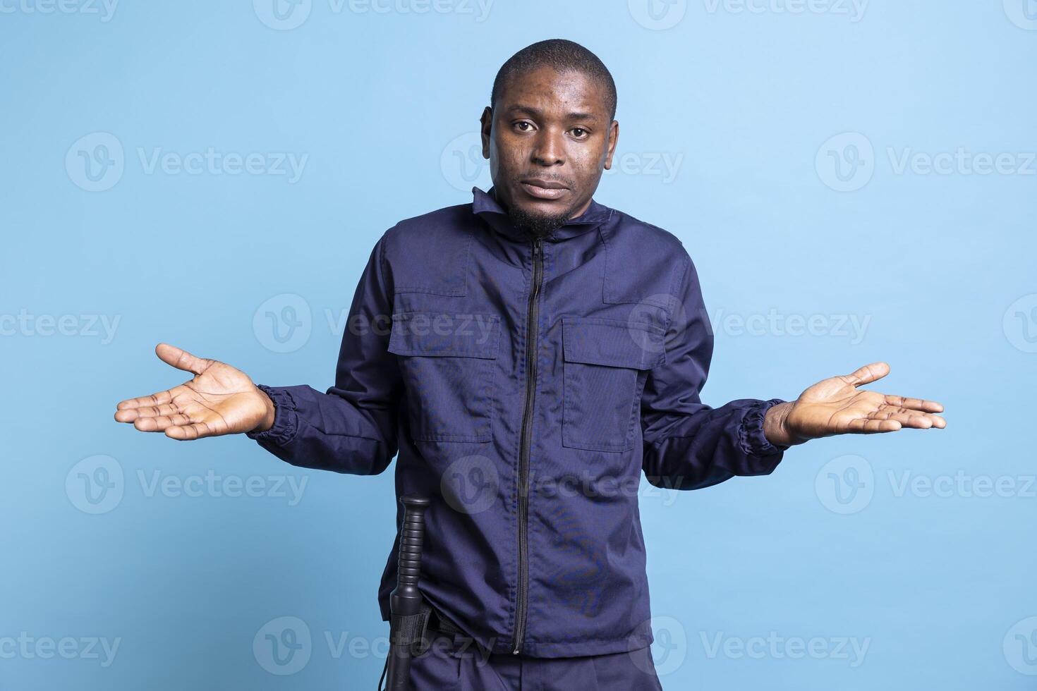 African american unsure security officer does i dont know symbol on camera, raising his shoulders and acting clueless or confused about something. Doubtful bodyguard is uncertain in studio. photo
