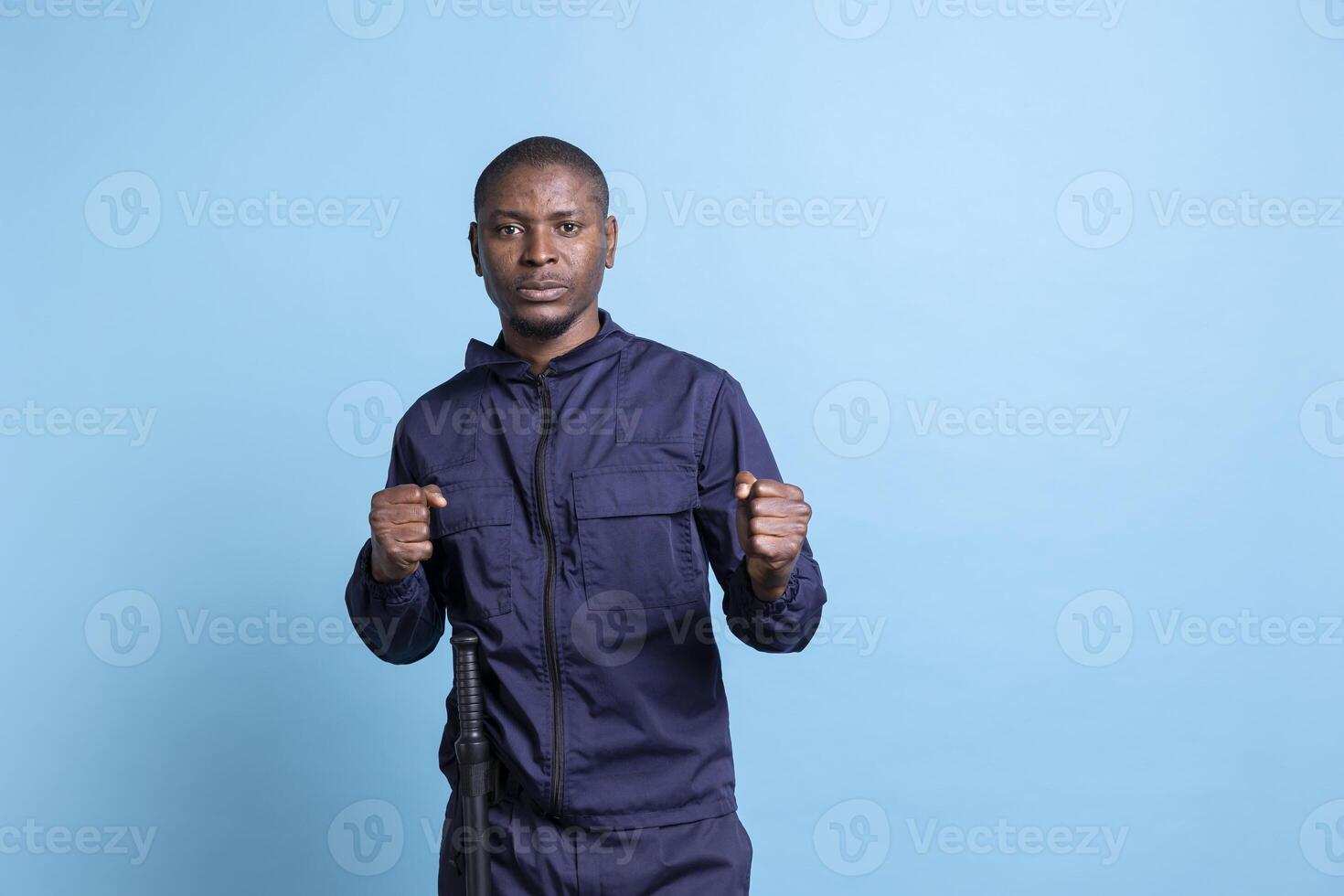 Professional security agent with clenched fists is ready for a fight in studio, throw punches while on protection and defense duty. Guard protecting the premises, taking safety measures and fighting. photo