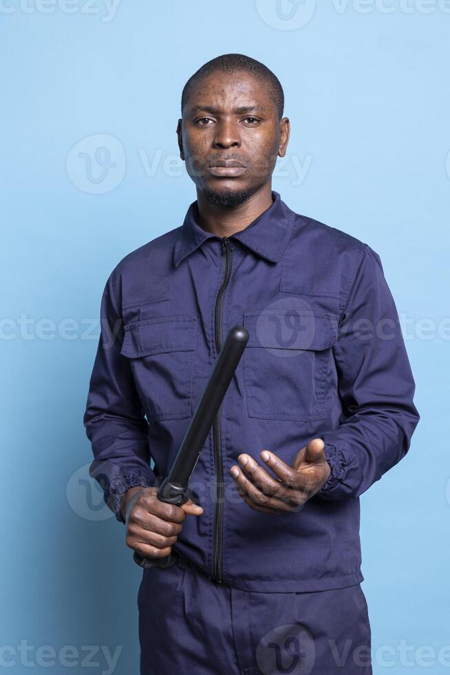 Armed security guard holding his baton and getting ready for an attack, trained to fight for protection if necessary. Professional male agent in uniform preparing for any emergency. photo