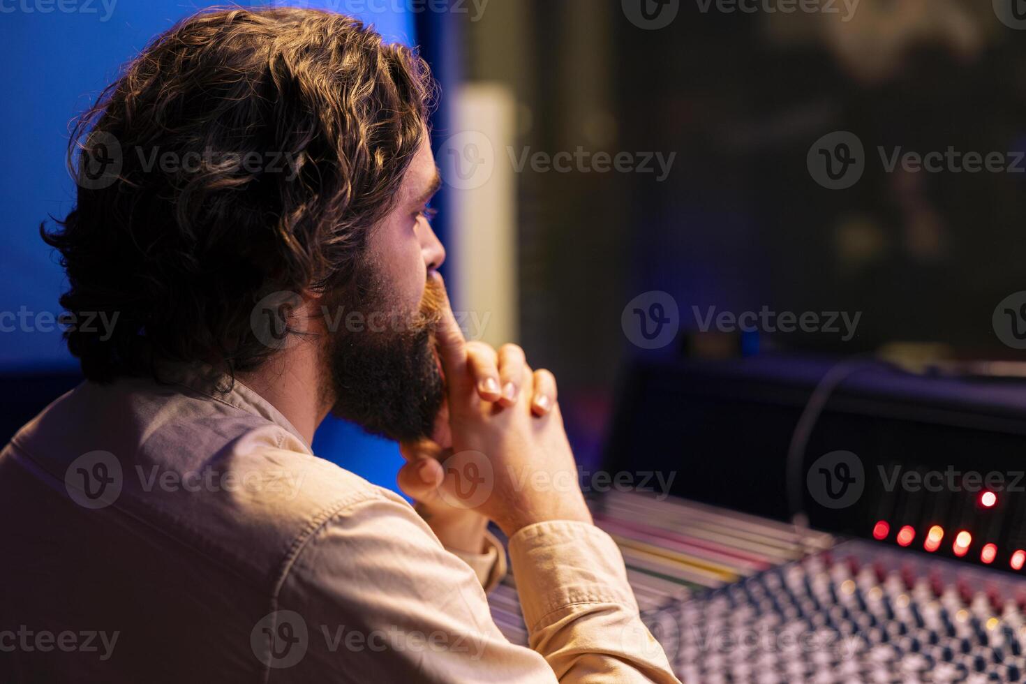 Music engineer working on mixing and mastering tunes with digital software, editing music with audio console control desk. Skilled sound technician creating tracks in professional studio. photo